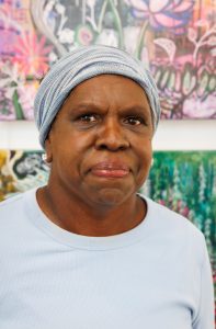 Portrait photograph of Marilyn Kepple in front of her artwork